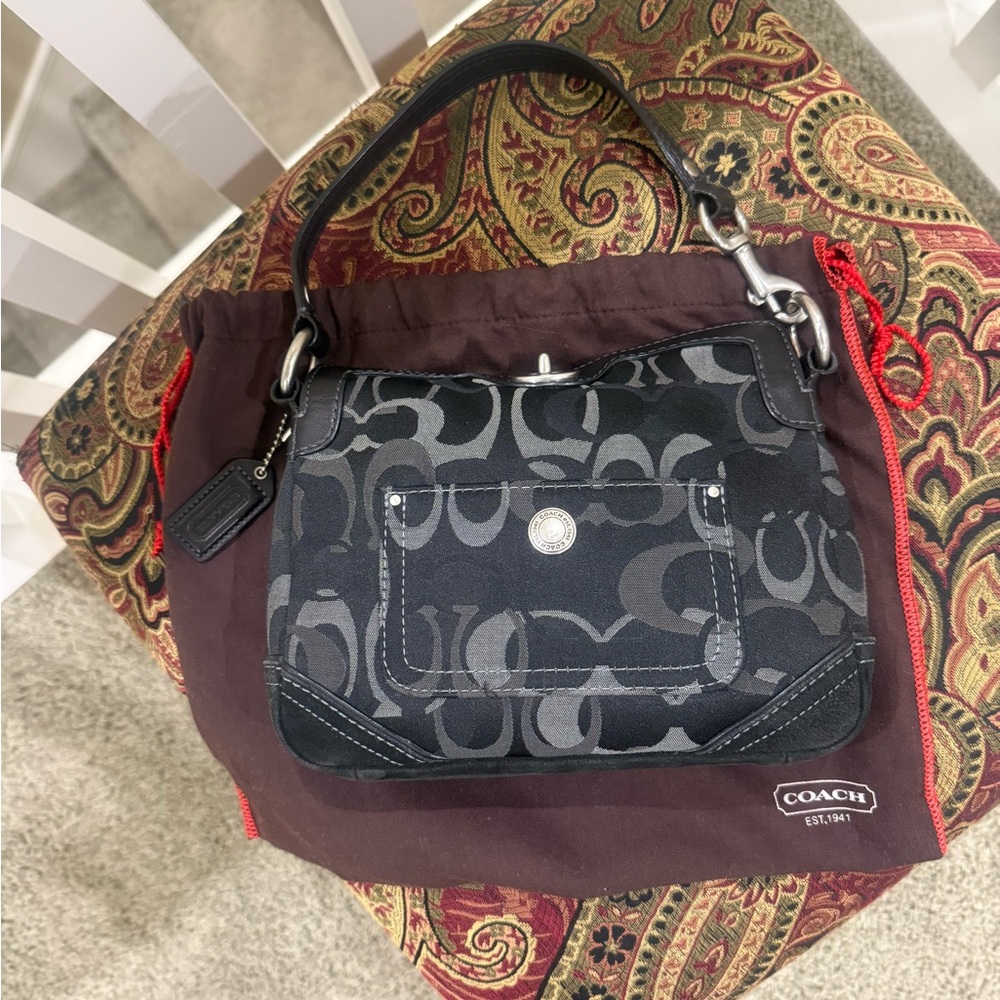 Small black Coach bag with woven print and unique closure.